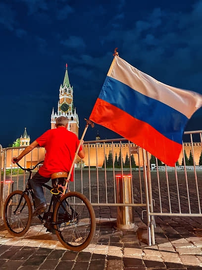 Мужчина на велосипеде с государственным флагом России на Красной площади