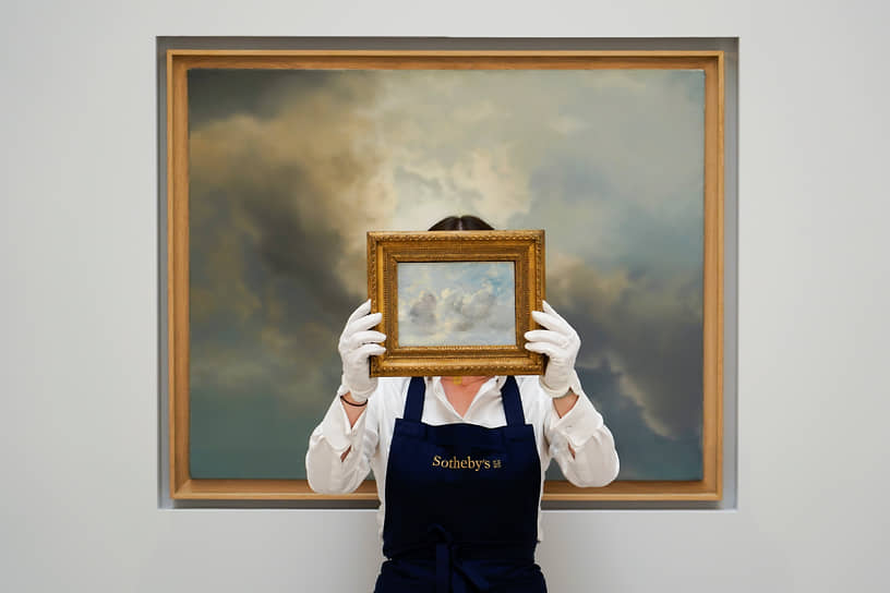 Лондон, Великобритания. Сотрудница Sotheby’s держит картину «Этюд облаков» Джона Констебла на фоне «Этюда облаков» Герхарда Рихтера на аукционе