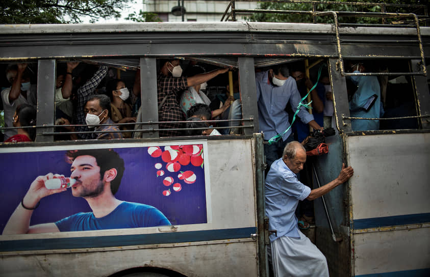 Кочи, Индия. Мужчина без маски выходит из переполненного автобуса 