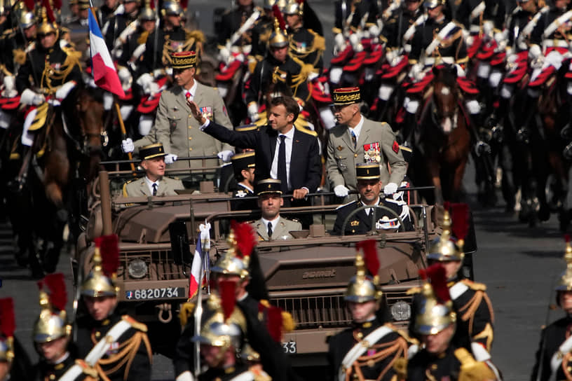 Президент Франции Эмманюэль Макрон (в центре) совершил смотр парадного построения, проехав по Елисейским полям на открытом армейском внедорожнике