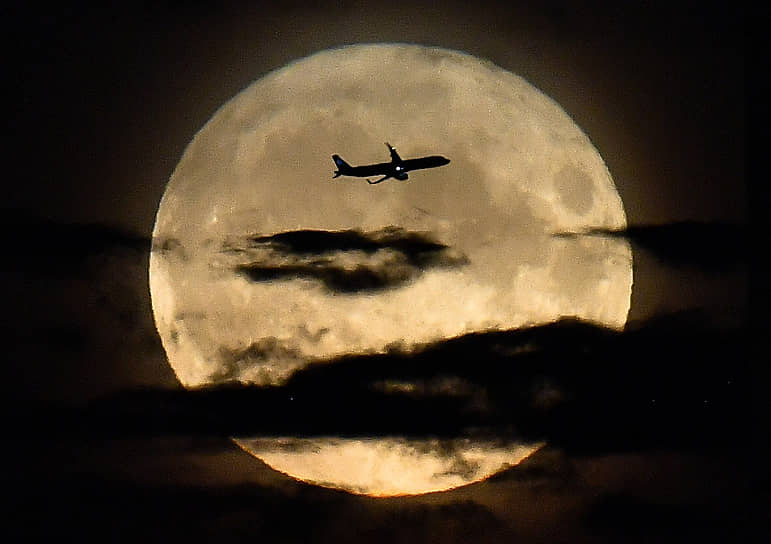 Самолет на фоне полной Луны в небе над Москвой