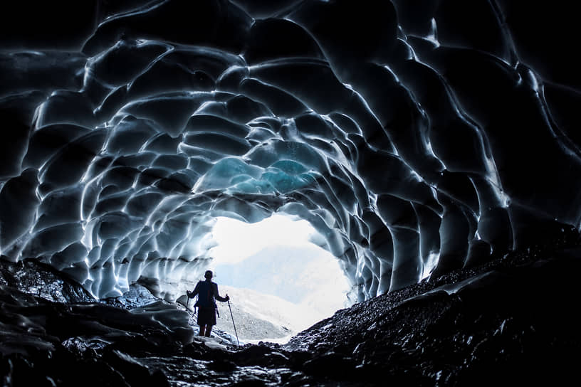 Феттис, Швейцария. Человек идет через пещеру внутри ледника в Сардоне