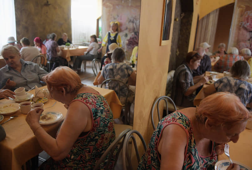Пожилые люди во время обеда в социальной столовой