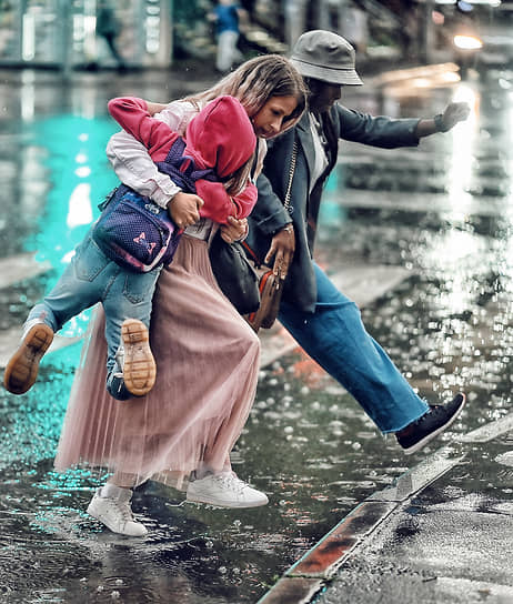 Москва. Женщины перепрыгивают лужу на пешеходном переходе во время сильной грозы