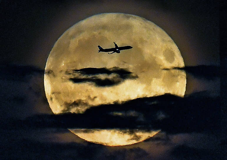 Москва. Самолет на фоне полной луны во время суперлуния