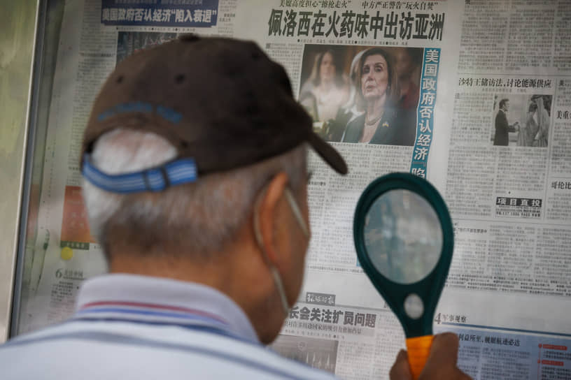 Пекин. Мужчина читает газету со статьей на первой полосе об азиатском турне спикера Палаты представителей США Нэнси Пелоси