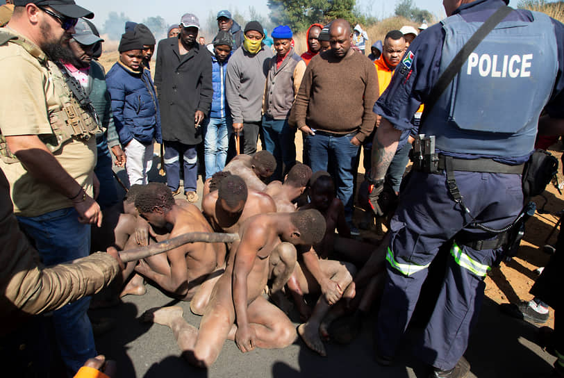 Крюгерсдорп, ЮАР. Местные жители наблюдают за задержанием нелегальных рабочих золотого рудника, подозреваемых в нападении на съемочную группу и изнасиловании моделей на одной из заброшенных шахт