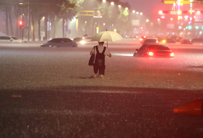 Мужчина идет через затопленную улицу 