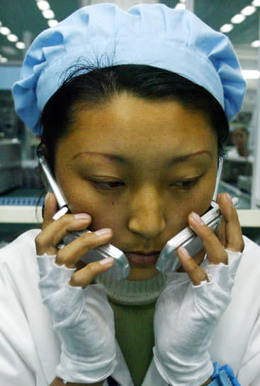 Нинбо, провинция Чжэцзян. Работница завода Ningbo Bird Co. Ltd тестирует мобильные телефоны 