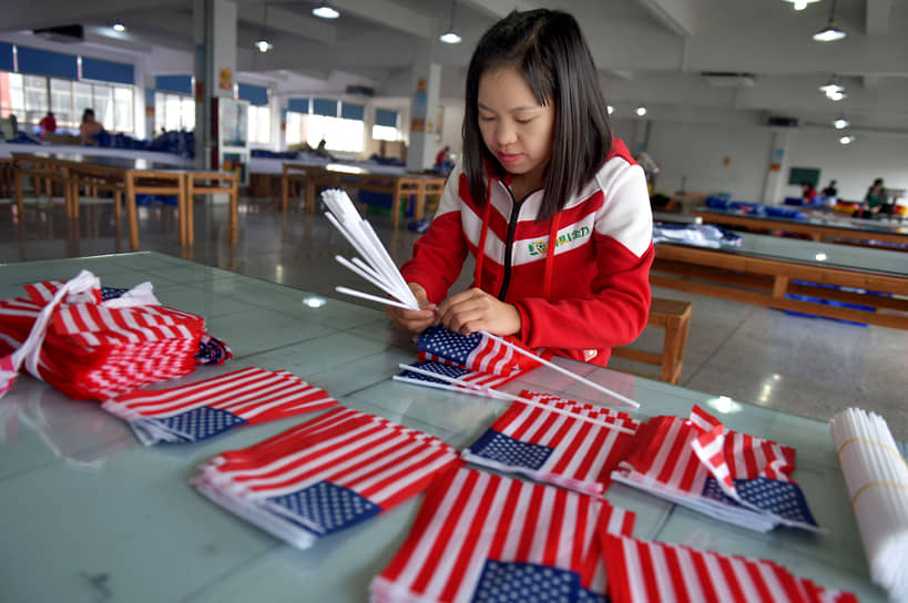 Цзиньхуа, провинция Чжэцзян. Работница текстильной фабрики собирает американский флаг