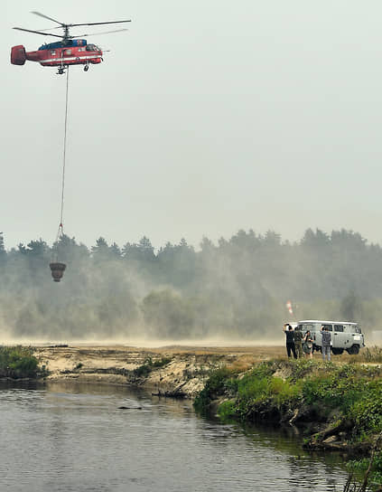 Вертолет МЧС набирает воду из реки 