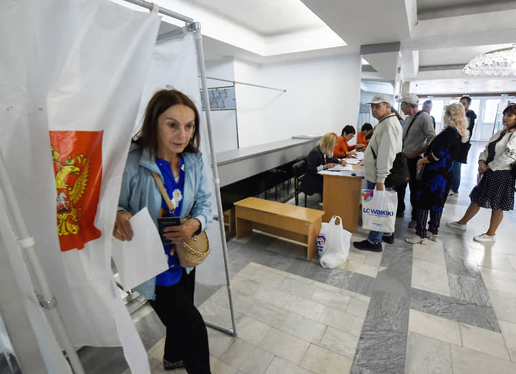 Женщина выходит из кабинки для голосования в Севастополе