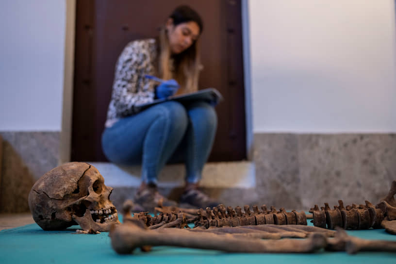Судмедэксперт со скелетом после эксгумации одной из братских могил