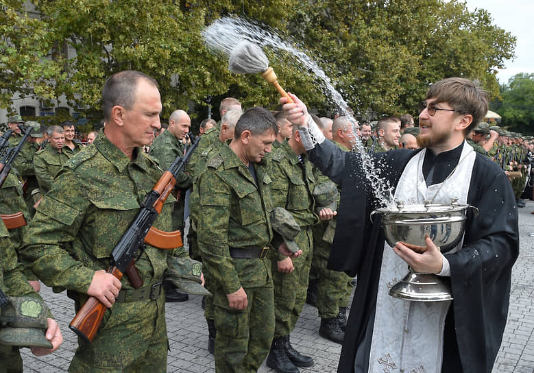 Священник окропляет мобилизованных мужчин на площади Нахимова в Севастополе