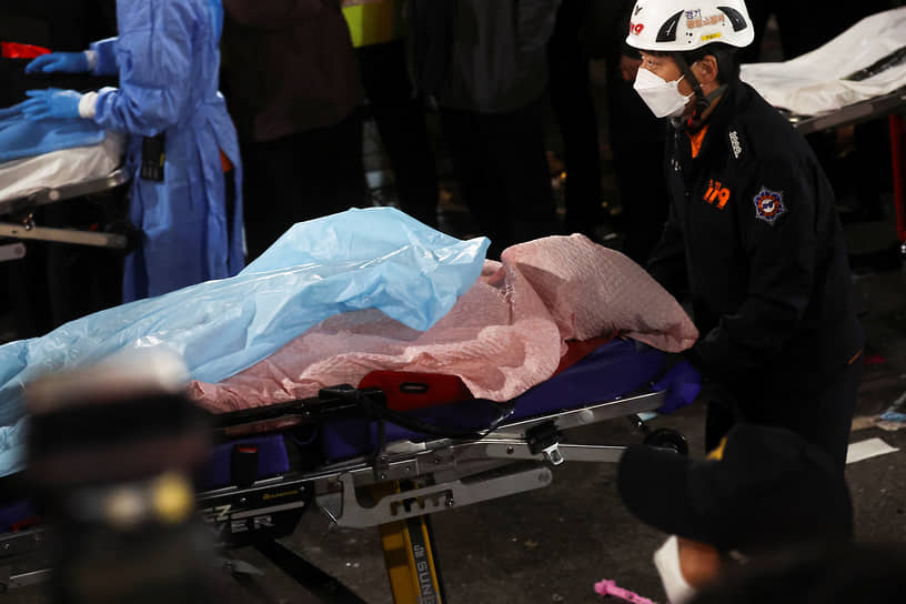 Спасатели несут тело погибшего в давке