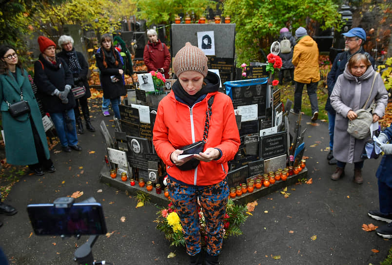 Женщина зачитывает имена репрессированных граждан на Донском кладбище у общей могилы №1