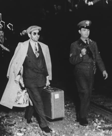 11 апреля 1947 года Лучано прибыл в Геную (на фото слева), где был арестован и отправлен в тюрьму в Палермо. Через месяц его отпустили. Остаток жизни гангстер провел в Италии под строгим надзором полиции&lt;br>
На фото: полицейский сопровождает Чарльза Лучано в Палермо, апрель 1947 года