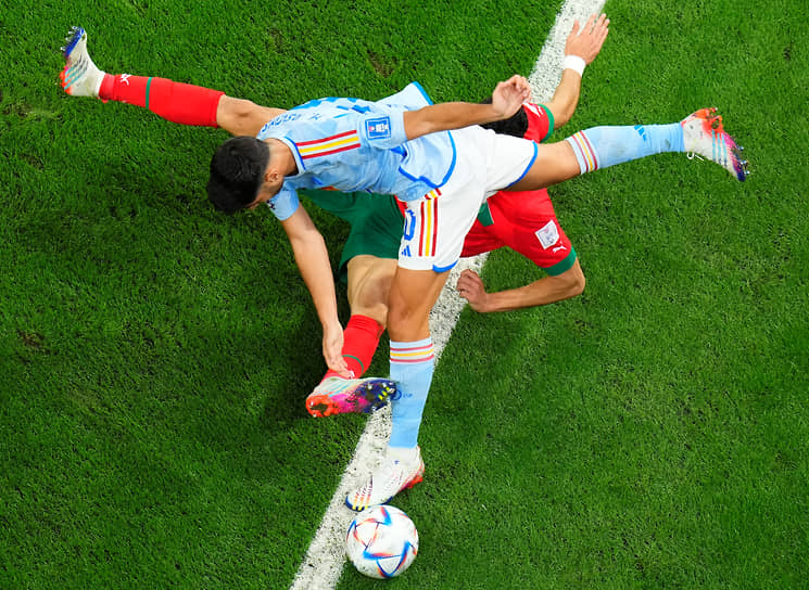 Испанский футболист Марко Асенсио борется за мяч с игроком сборной Марокко Найефом Агердом (в красном) 