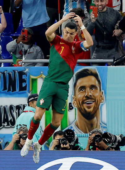Капитан португальской сборной Криштиану Роналду празднует забитый гол в матче против Ганы на фоне плаката с портретом аргентинского нападающего Лионеля Месси 