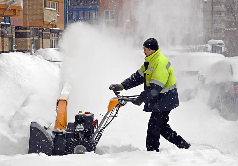 Сотрудник коммунальных служб убирает снег