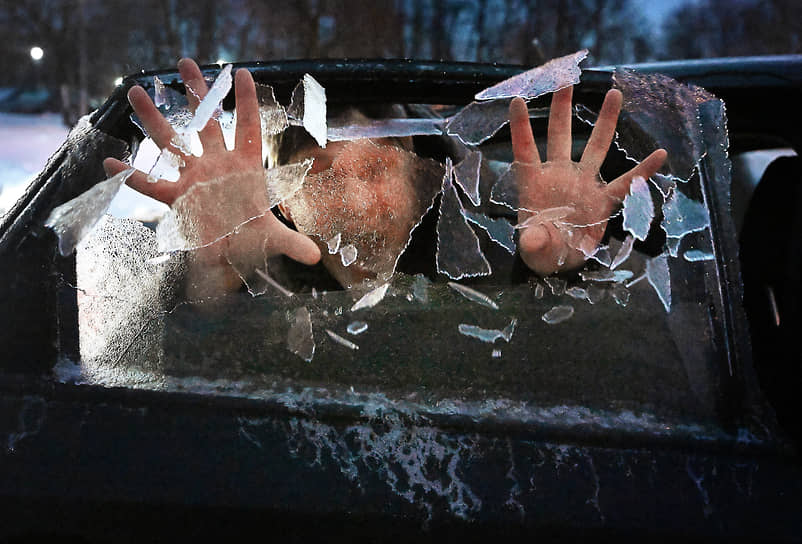 Мужчина разбивает наледь на окне автомобиля