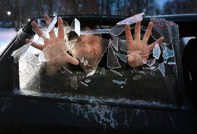 Мужчина разбивает наледь на боковом окне автомобиля