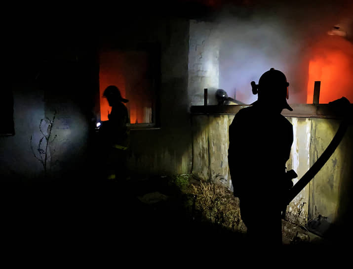 Сотрудники пожарной службы МЧС ДНР тушат огонь после обстрела Петровского района Донецка