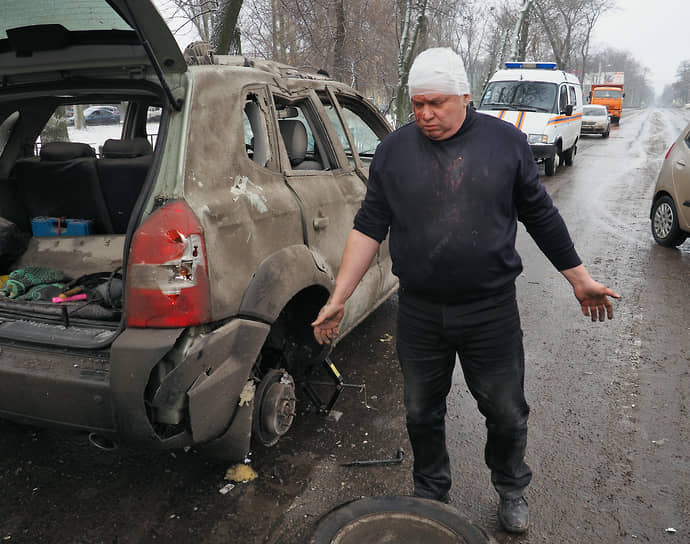 Мужчина у разбитого автомобиля, пострадавшего после обстрела в Донецке