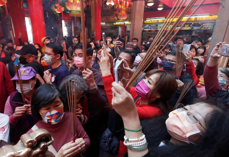 У жителей Азии существует поверье, что красный цвет отгоняет злых духов и приносит удачу. Поэтому в праздничные дни везде преобладает этот цвет&lt;br>
На фото: Тайбэй, Тайвань. Верующие в медицинских масках в храме встречают первый день лунного Нового года