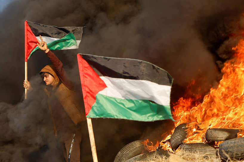 Газа. Палестинец с флагом, участвующий в столкновении с израильскими войсками недалеко от границы 