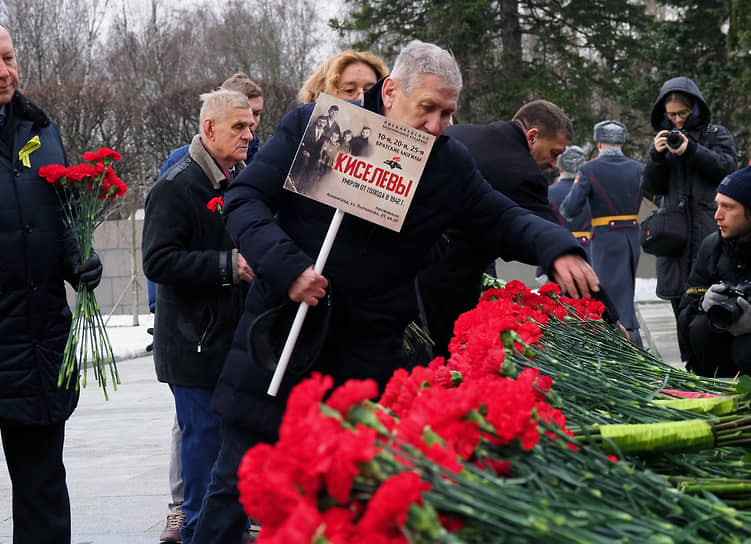 Мужчина кладет цветы к монументу «Мать-Родина» на Пискаревском кладбище