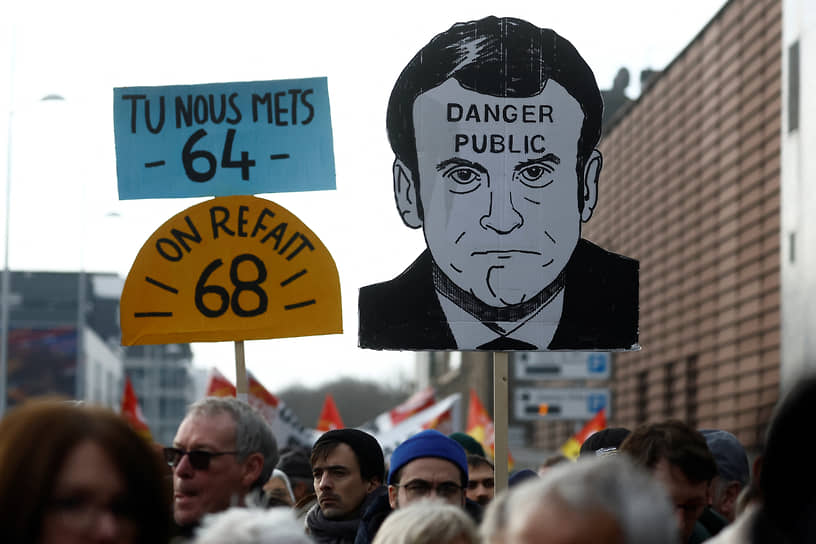 Протестующие в Сен-Назере держат плакат с портретом президента Макрона 