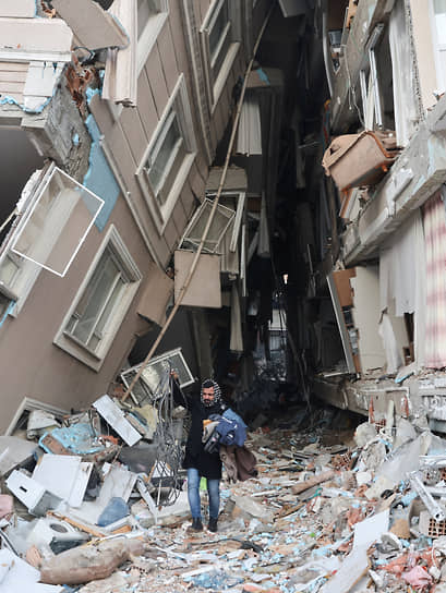 Выживший после землетрясения мужчина выносит вещи из своей разрушенной квартиры в Хатае (Турция)