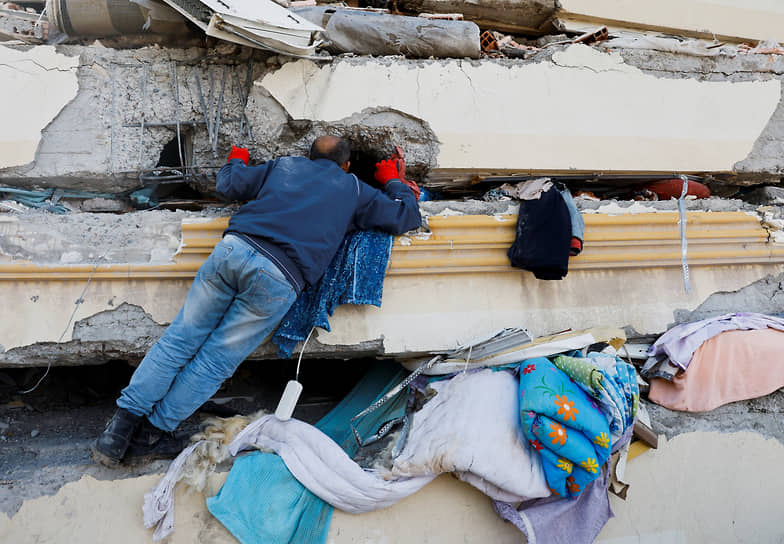 Мужчина осматривает рухнувшее здание в Кахраманмараше (Турция)