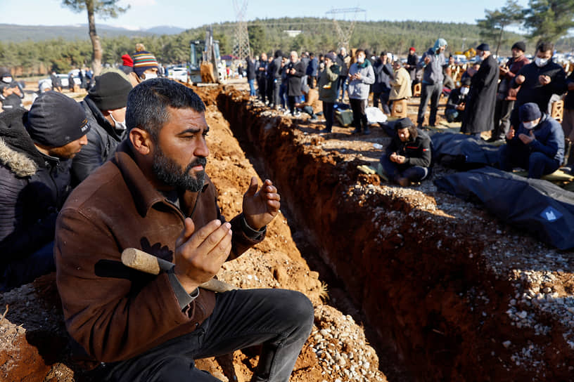 Кахраманмараш, Турция. Люди молятся перед погребением тел жертв землетрясения на импровизированном кладбище 