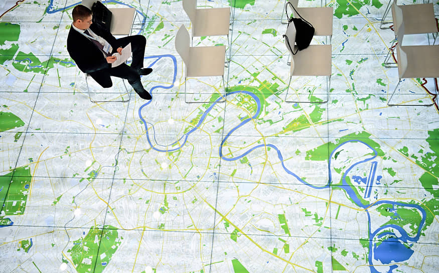 Москва. Участник ежегодного форума «Технологии большого города» на фоне интерактивной карты Москвы