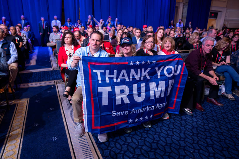 Поддержка Дональда Трампа держит флаг во время его выступления