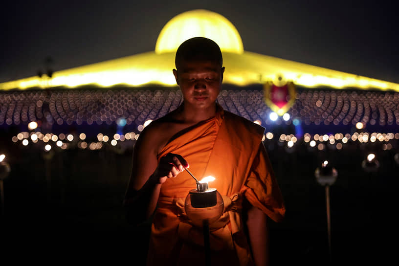 Бангкок, Таиланд. Монах храма Ват Пхра Дхаммакая зажигает свечу в честь буддийского праздника Макха Буча