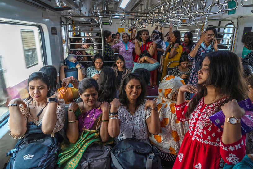 Мумбаи, Индия. Пассажиры пригородного поезда принимают участие в занятиях йогой, организованных в честь Международного женского дня