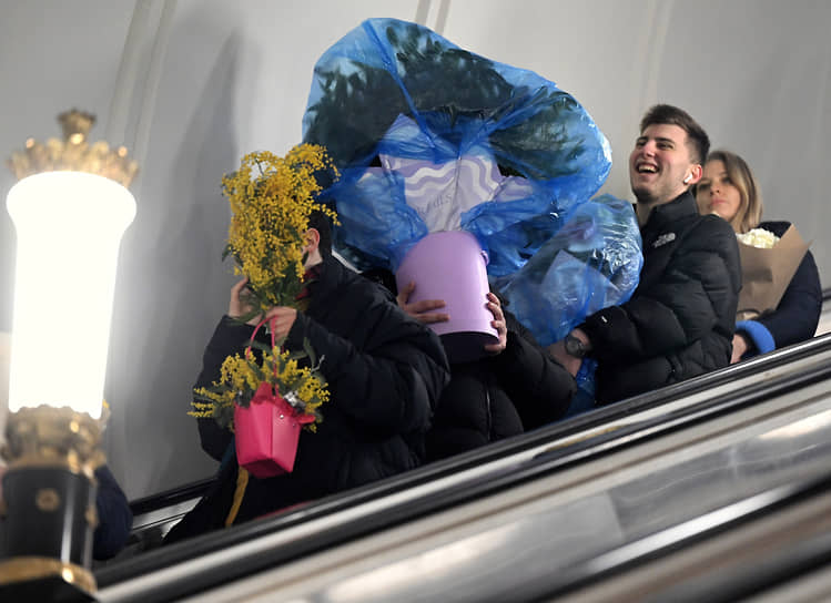 Москва, Россия. Пассажиры с букетами цветов на эскалаторе на станции метро «Рижская»