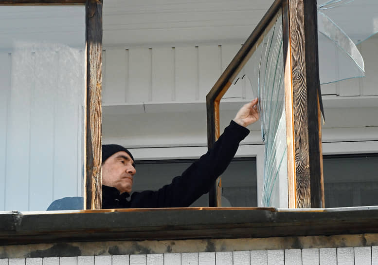 Житель Донецка убирает осколки стекла из оконной рамы после обстрела города