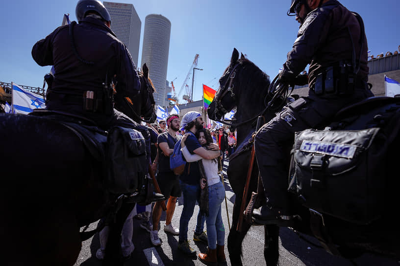 Тель-Авив, Израиль. Протестующие против судебной реформы обнимаются, пока полицейские разгоняют участников акции