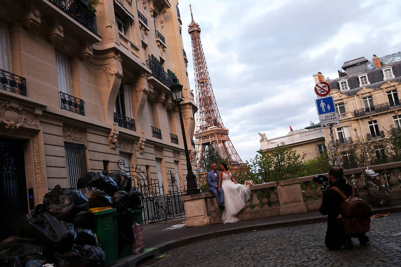 Париж, Франция. Молодожены фотографируются неподалеку от переполненных баков с мусором, который не вывозят уже больше трех недель из-за протеста коммунальщиков против пенсионной реформы