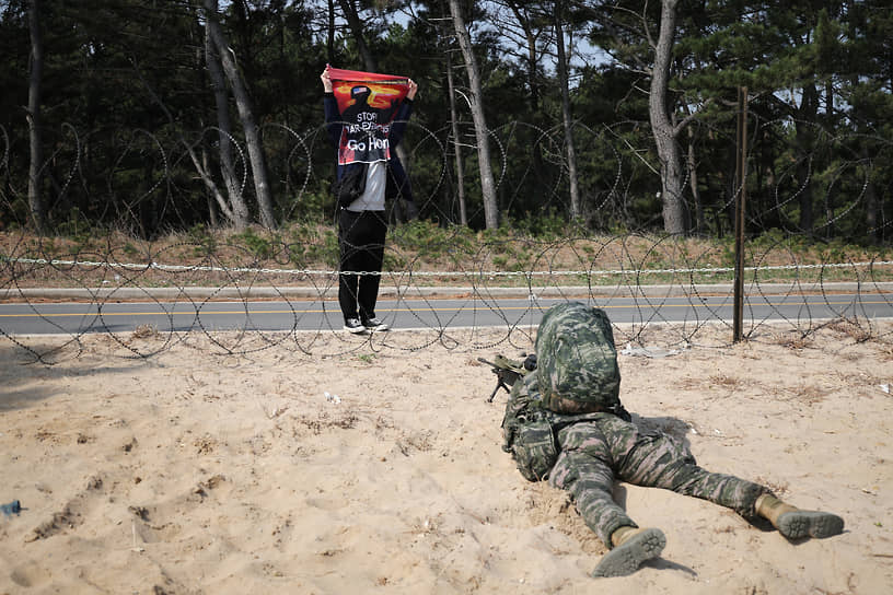 Пхохан, Южная Корея. Активист с антивоенным плакатом у места проведения совместных учений морской пехоты США и Южной Кореи
