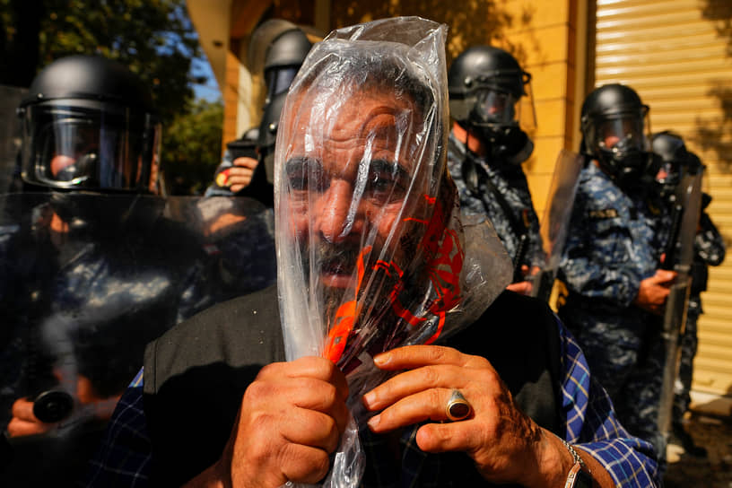 Бейрут, Ливан. Бывший сотрудник ливанских сил безопасности защищается пакетом от слезоточивого газа, который распыляют на акции протеста правительственные силы