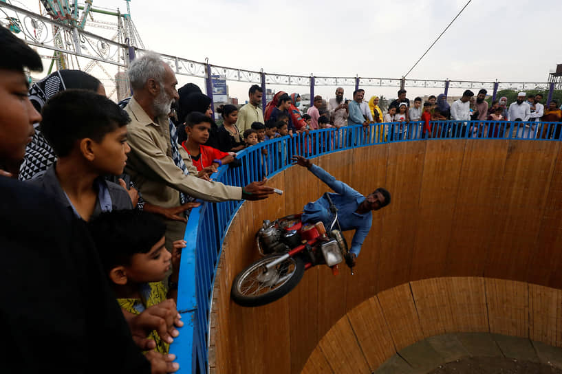 Карачи, Пакистан. Мотоциклист собирает деньги у зрителей, исполняя трюк «Колодец смерти» 