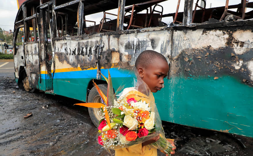 Найроби. Мальчик с букетом цветов на фоне автобуса, подожженного в ходе протестов сторонников лидера кенийской оппозиции Раила Одинги