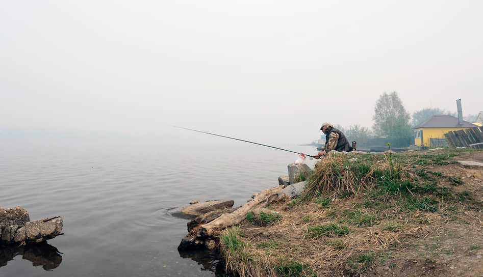 Рыбак на фоне дыма от лесных пожаров в Режевском городском округе Свердловской области