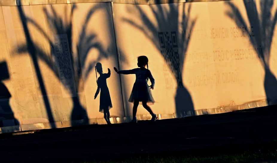 Адлер. Девочка играет с тенью на заборе