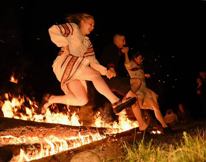 Участники фестиваля перепрыгивают через огонь